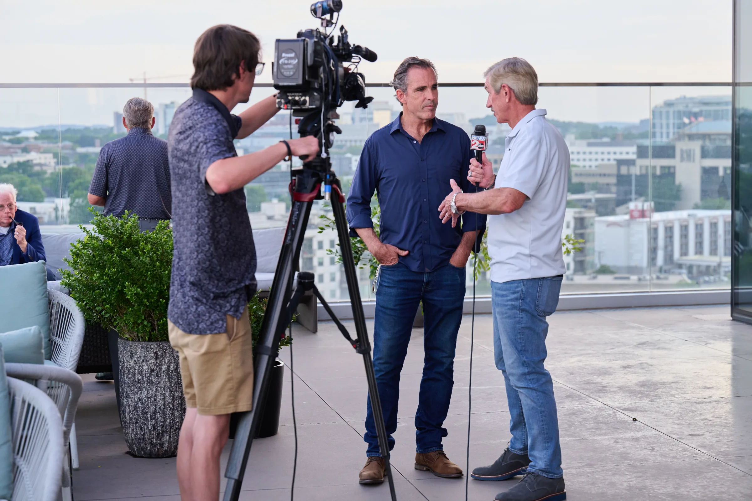 Two men being interviewed on a rooftop with a camera crew.