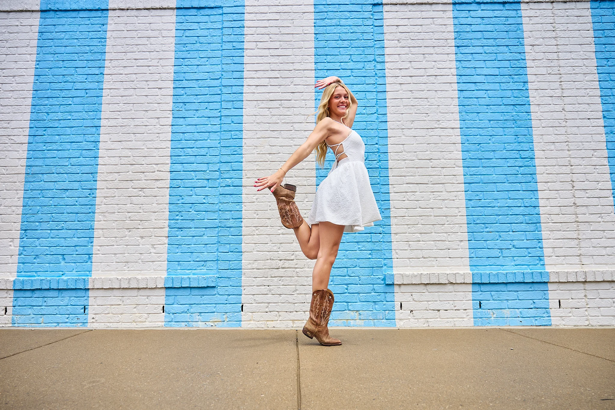 Blue striped Nashville mural photo stop with cowboy boots and white dress