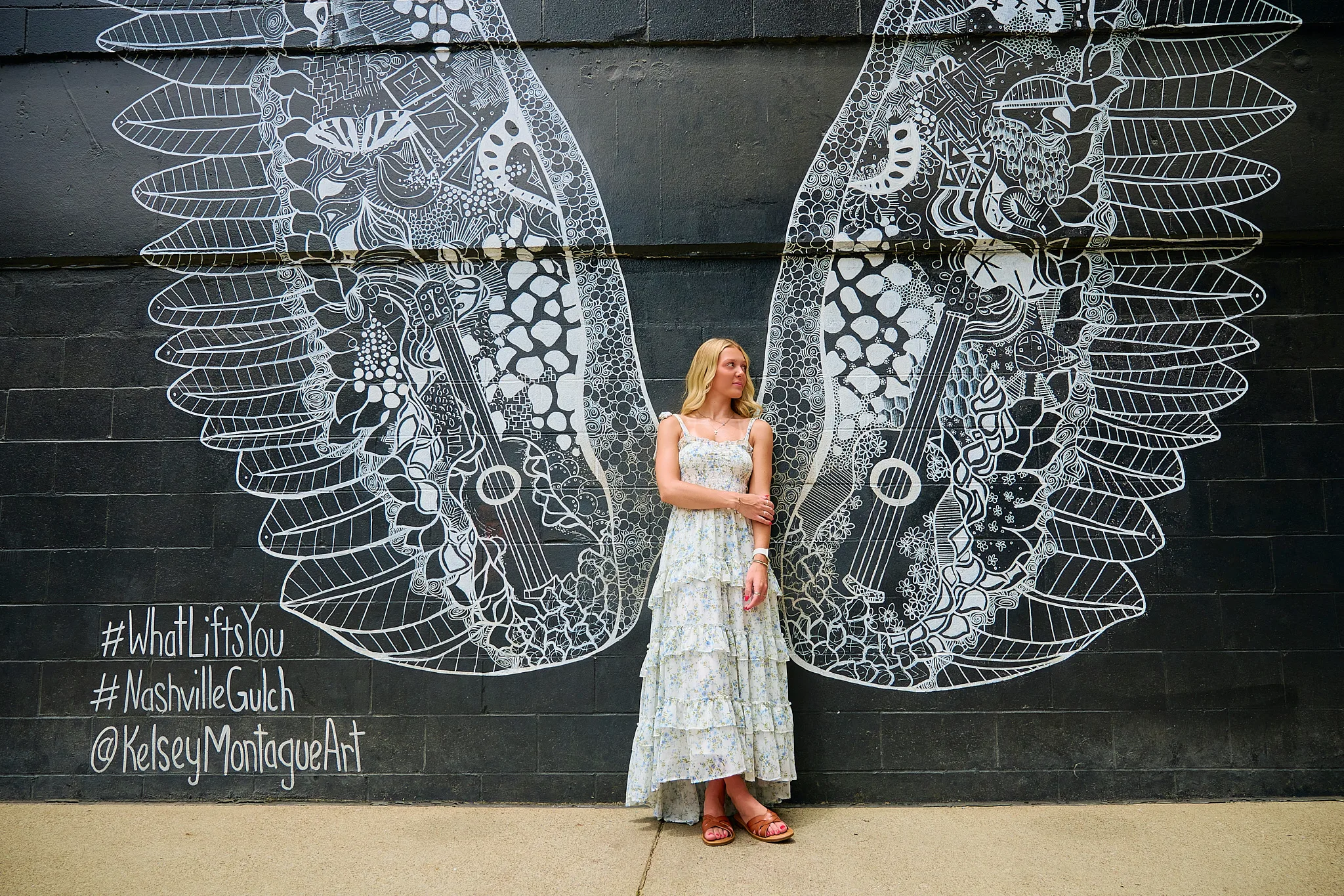 Woman posing in front of a large mural with wings in Nashville.