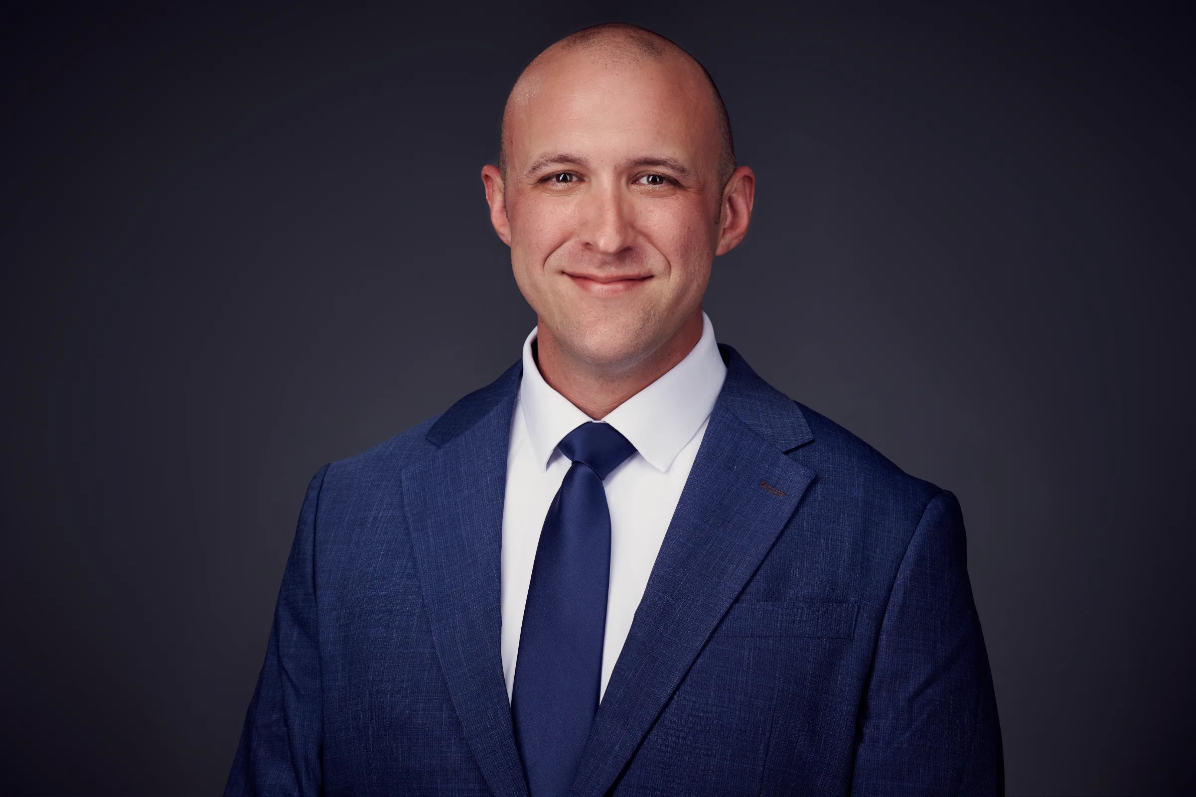 Professional headshot of a man in a blue suit and tie.