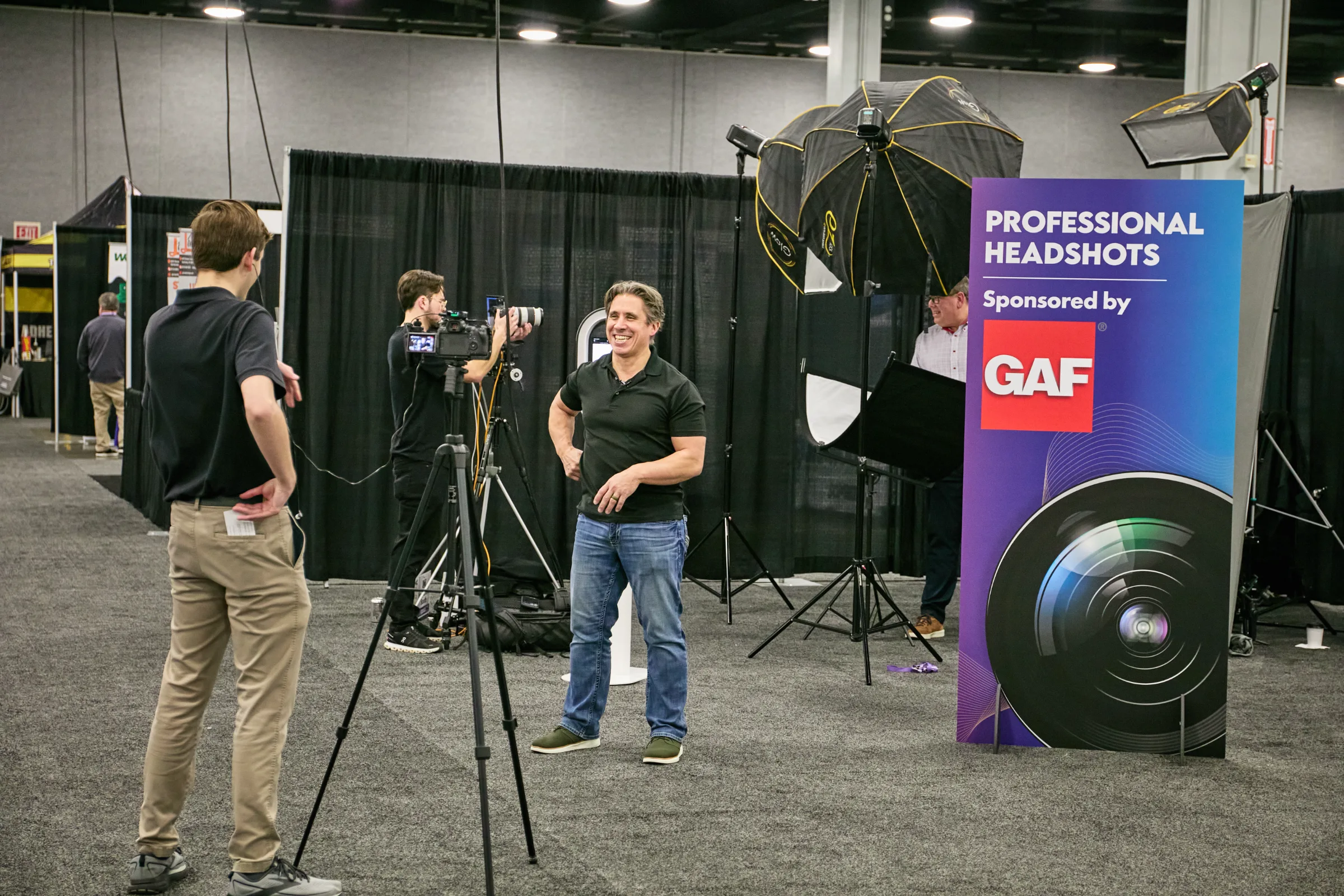 Two men at a photography booth with a backdrop for professional headshots.